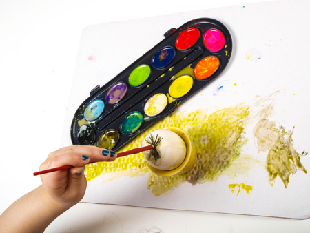 Little girls hands playing with colorful paint, creating Easter decorationの写真素材
