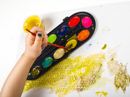 Little girls hands playing with colorful paint, creating Easter decorationの写真素材