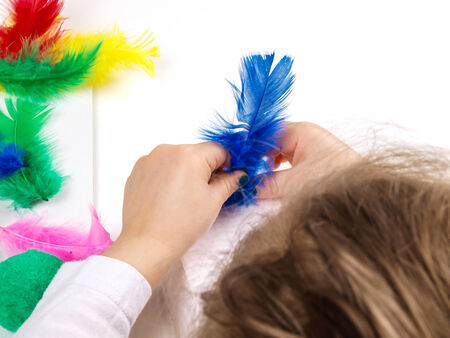 Little girls hands playing with colorful feathers, creating Easter decorationの写真素材