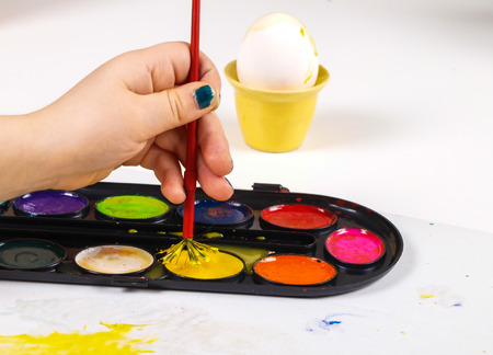 Little girls hands playing with colorful paint, creating Easter decorationの写真素材