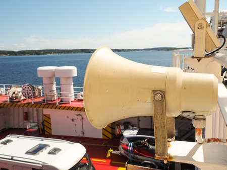 Speaker attached onto railing on boat above cars on deckの写真素材