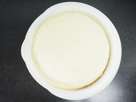 Proven dough in a white plastic bowl on black tableの写真素材