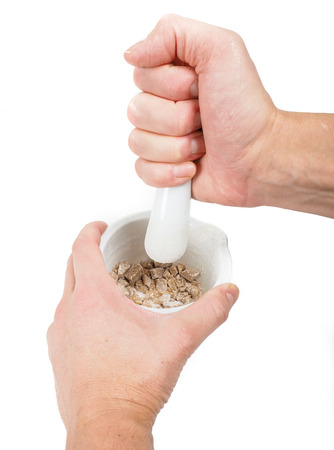 Person crushing brown sugar cubes in a white marble mortarの写真素材