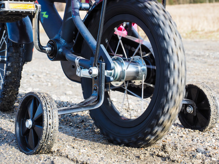 Bicycle with supporting wheels stuck in loose gravelの写真素材