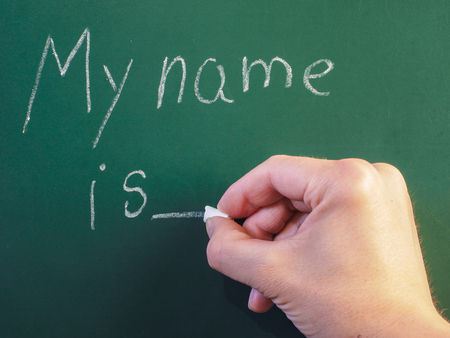 Teacher writing on green chalkboard: My name isの写真素材