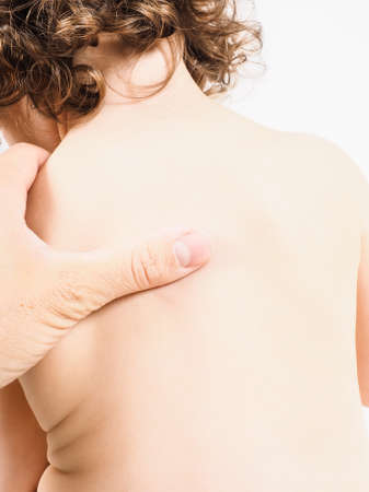 Pediatrician having health check on unrecognizable child with thumb pressure massage on backの写真素材