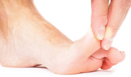 Male person pulling big toe backwards isolated towards whiteの写真素材