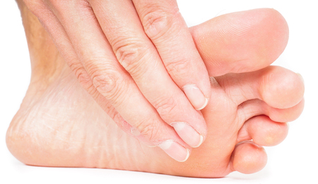 Person having pedicure, pulling hand under foot towards white backgroundの写真素材