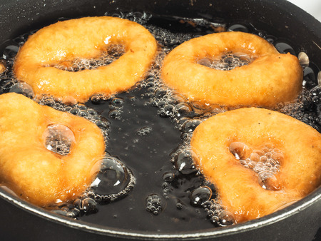 Closeup of doughnuts boiling in kettle of oilの写真素材