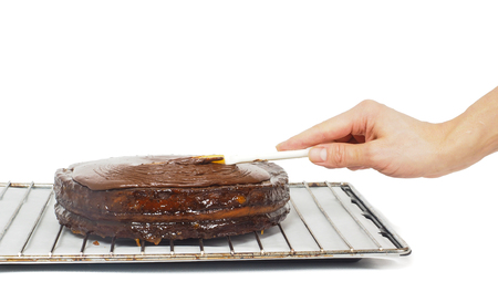 Pastry chef making final touches to a sacher chocolate cake with icingの写真素材