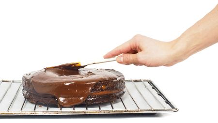 Pastry chef making final touches to a sacher chocolate cake with icingの写真素材