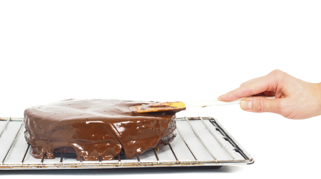 Pastry chef making final touches to a sacher chocolate cake with icingの写真素材