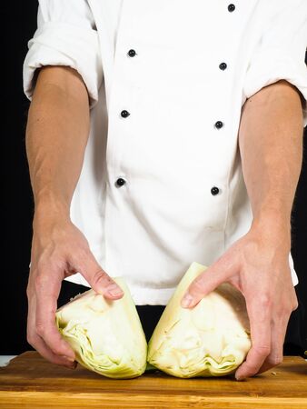 Professional chef showing a cabbage cut into two pieces on a wooden boardの写真素材