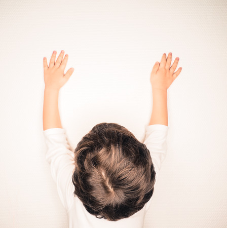Closeup of beautiful brown hair on unrecognizable boy, stretching up a wall indoorsの写真素材