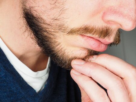 Male person, at closeup with fingers in beardの写真素材