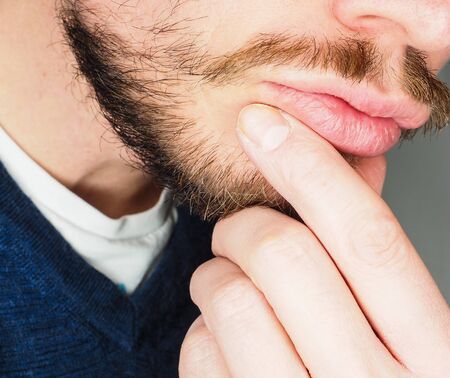 Male person, at closeup with fingers in beardの写真素材
