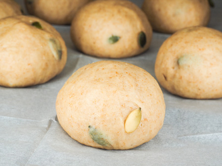 Pumkin seed buns proofing on baking paper at close-upの写真素材