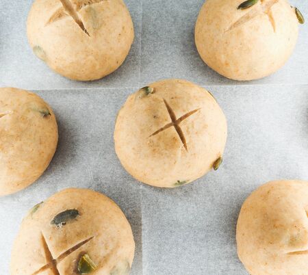Pumkin seed buns proofing on baking paper at close-up