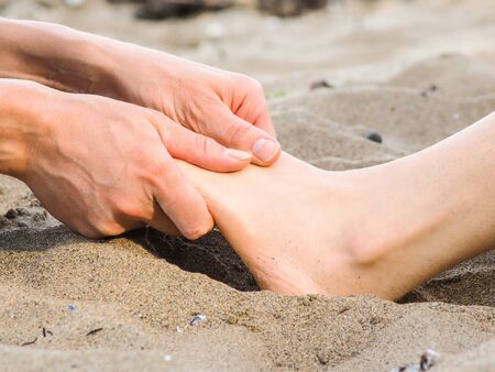 Foot massage on a beach in sand, male and female caucasianの写真素材