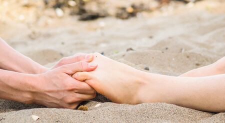 Foot massage on a beach in sand, male and female caucasianの写真素材