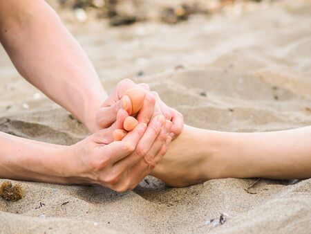 Foot massage on a beach in sand, male and female caucasianの写真素材