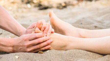 Foot massage on a beach in sand, male and female caucasianの写真素材