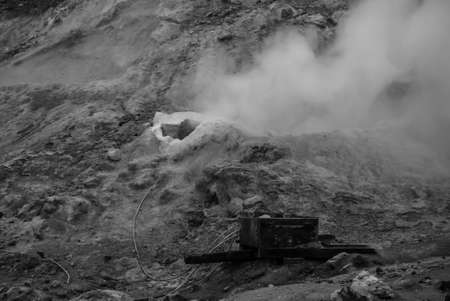 Sulfuric smoke rising from a hole in the groud black and white