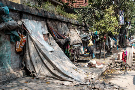 Kolkata, India - February 1, 2020: An unidentified man sleeps on the ground next to run down tarp shelter homes on February 1, 2020 in Kolkata, Indiaのeditorial素材