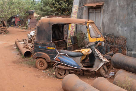 Bhubaneswar, India - February 4, 2020: An old abandoned auto rickshaw and a motorbike covered in...