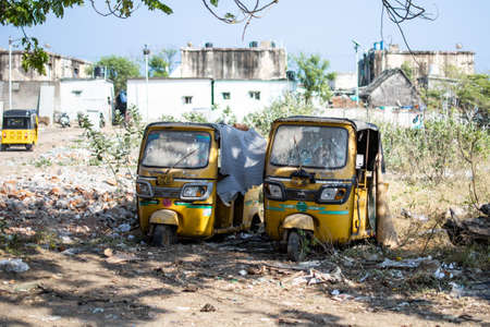 Chennai, India - February 8, 2020: Two traditional yellow auto rickshaws abandoned and forgotten on...