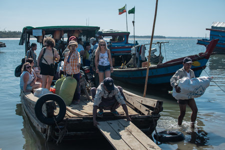 Chaung Thar, Myanmar - December 26, 2019: Local people and tourists disembark from a small boat ferry on December 26, 2019 in Chaung Thar, Myanmarのeditorial素材