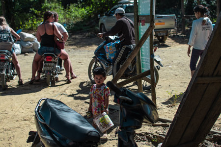 Ngwesaung, Myanmar - December 26, 2019: A young burmese child in a colorful dress holds a plstic bucket on December 26, 2019 in Ngwesaung, Myanmarのeditorial素材
