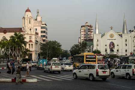Yangon, Myanmar - December 30, 2019: Traffic with public transport buses, cars and pedestrians near Sule Pagoda in downtown cityのeditorial素材