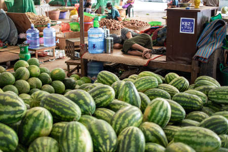 YANGON, MYANMAR - DECEMBER 31 2019: A local vendor sleeps next to a huge pile of fresh watermelonsin Myanmarのeditorial素材