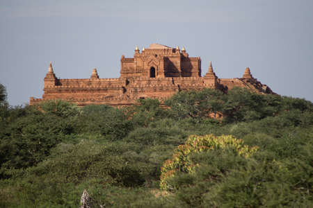 BAGAN, NYAUNG-U, MYANMAR - 3 JANUARY 2020: A huge old and historical temple pagoda upon a hill above the tree vegetationのeditorial素材