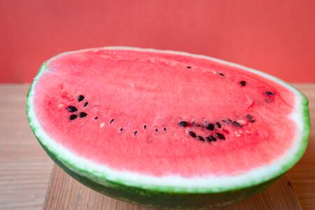Slices of watermelons on wooden table and red backgroundの写真素材