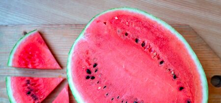 Slices of watermelons on wooden table and red backgroundの写真素材