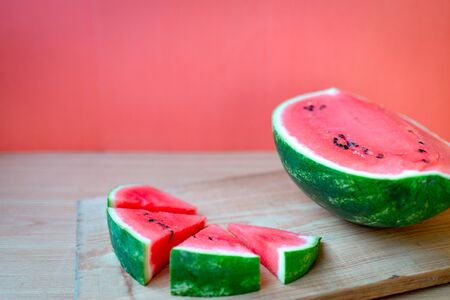 Slices of watermelons on wooden table and red backgroundの写真素材