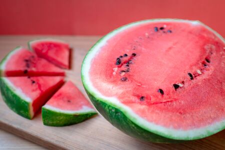 Slices of watermelons on wooden table and red backgroundの写真素材