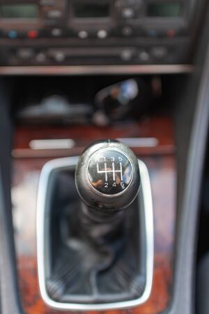 horizontal close up high angle image of a black and white manual car gear stick with the gearbox in a blurry backgroundの写真素材