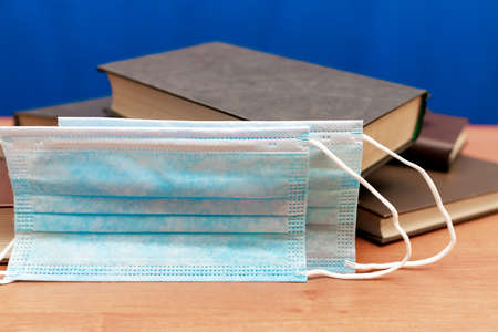 Covid pandemic concept.Books on the library table and protective medical two masksの写真素材