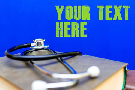 Stethoscope with stack of books on table or blue trendy background.Medical literature concept