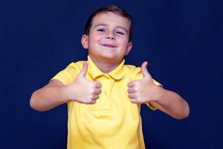 Nice young 9s boy shows a class with two thumbs up on a blue background.の写真素材