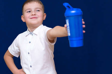 Portrait of happy little boy with water from plastic bottle on blue dark backgroundの写真素材