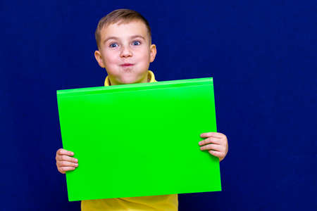 Happy nice calm caucasian child boy is swollen cheeks holding a poster for your information on the...