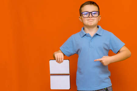 Caucasian schoolboy holding a Scrapbook banner isolated on orange studio backgroundの写真素材