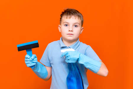 Housekeeping concept. Studio portrait of handsome kid child schoolboy in latex gloves cleaning glass...