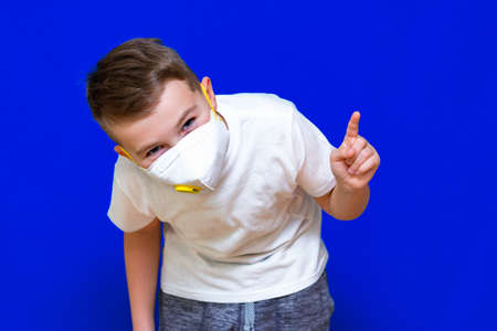 Close up Portrait of caucasian boy in a protective mask respirator showing at copy space bright blue background.の写真素材