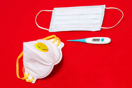 Top view photo.Coronavirus concept. White Surgical mask protective mask electronic thermometer shows...