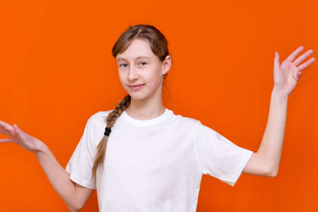 Close up portrait of happy youn child girl spreading hands aside, wearing casual white t-shirt,...